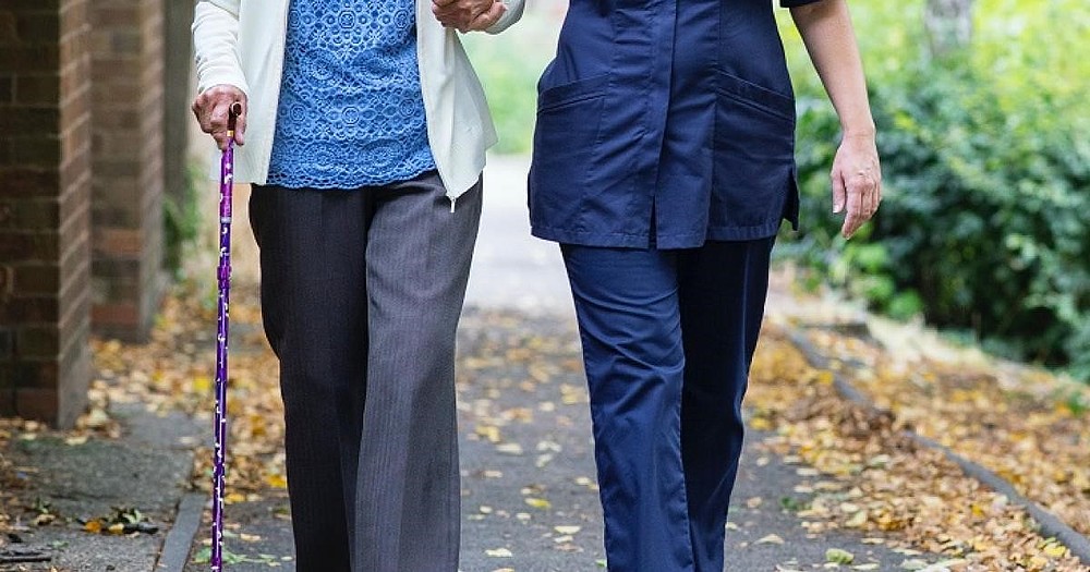 Pflegekraft mit älteren Menschen an der Hand