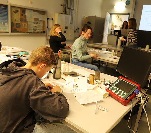Schülerinnen und Schüler basteln im Werkstofflabor an Papierfliegern.