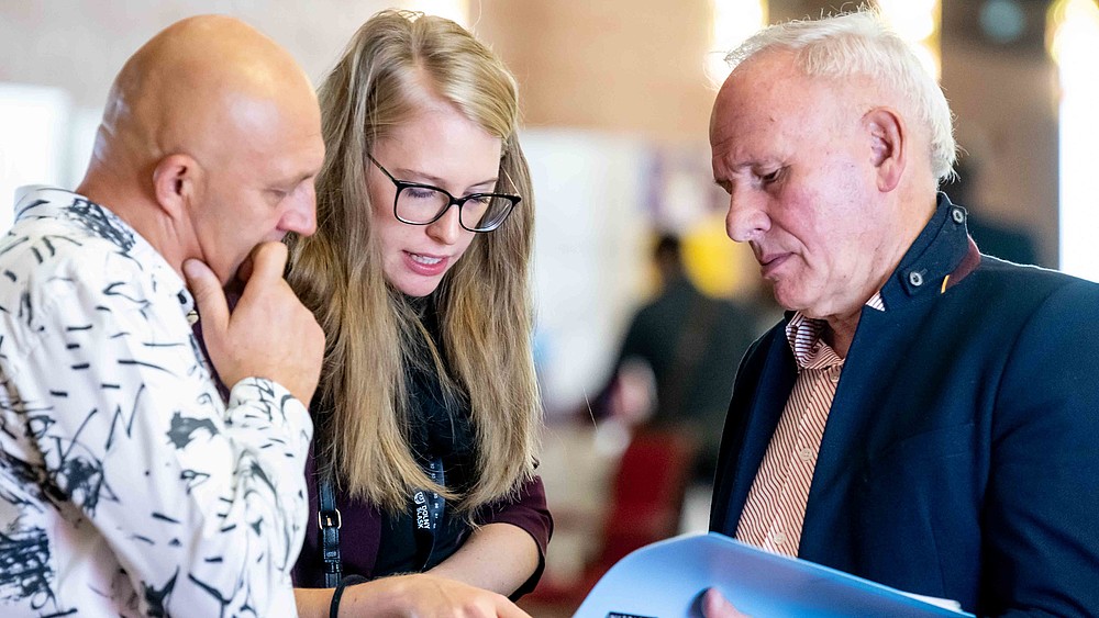 Besuchende schauen sich eine Broschüre an.