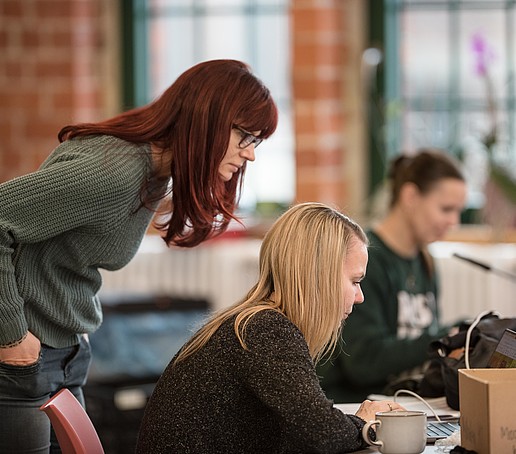 Mitarbeitende im Aufenthaltsbereich beim Check der Bildschirmeinstellungen, schauen auf den Laptopbildschirm