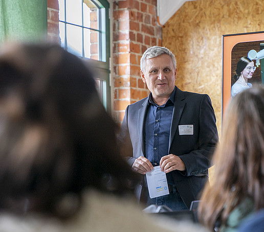 Ein Konferenzteilnehmer spricht vor den sitzenden Gästen.