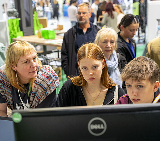 Besuchende schauen auf einen Bildschirm.