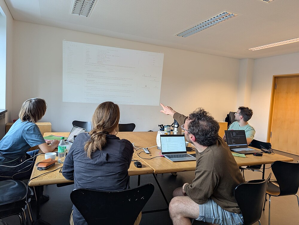 4 Personen schauen auf eine Leinwand