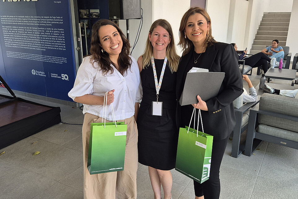 Zwei Frauen halten eine HSZG-Geschenketüte in der Hand, in der Mitte steht Patricia Stange.