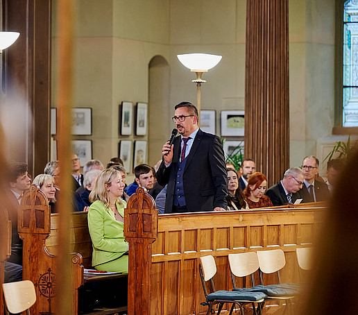 Prof. Meinert steht und spricht ins Mikro.