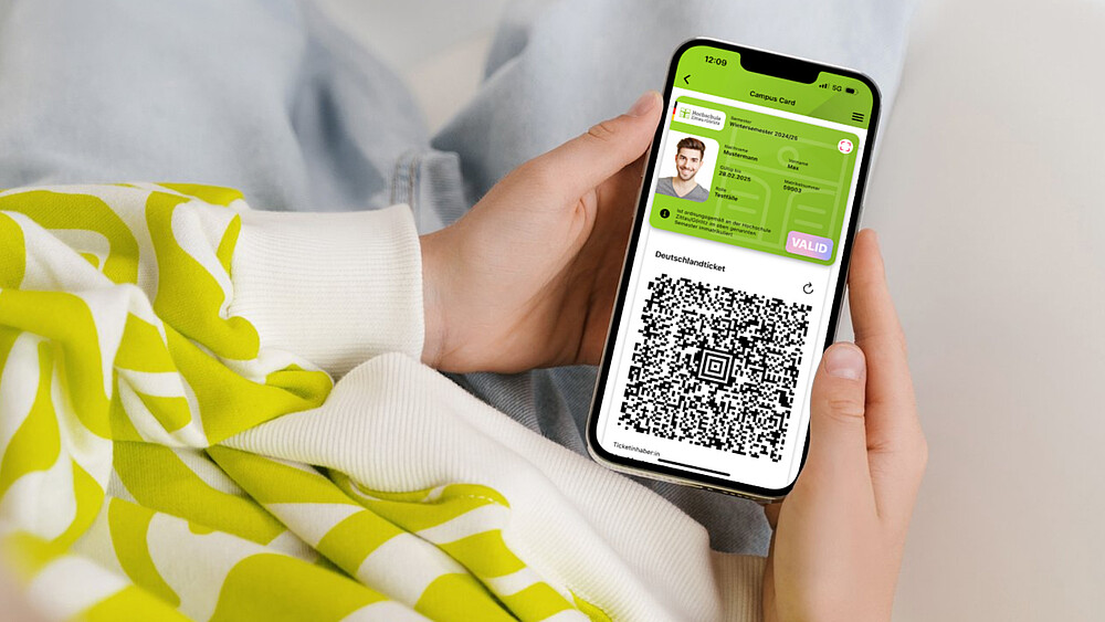 Ein Smartphone liegt in zwei Handflächen, auf dem Display ist der digitale Studierendenausweis zu sehen.