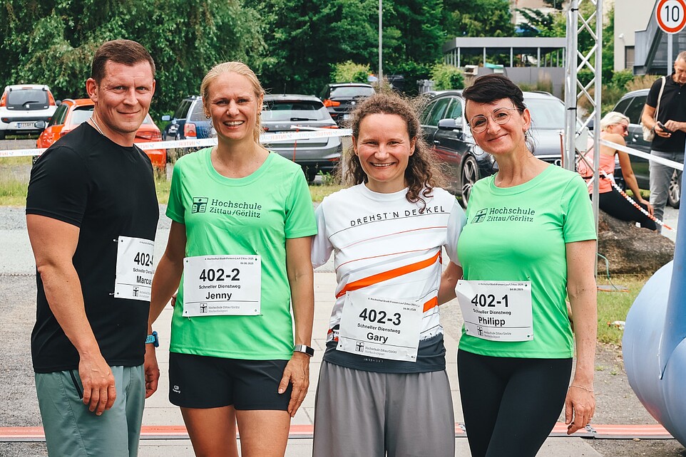 Vier Laufteilnehmende stehen nach dem Zieleinlauf nebeneinander und lächeln in die Kamera.