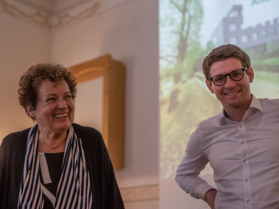 Mann + Frau lächelnd vor Leinwand