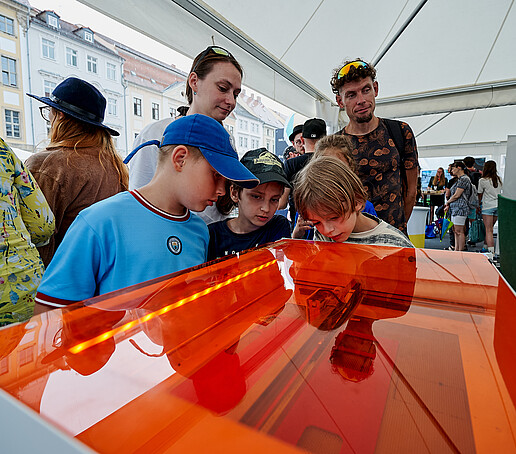 Kinder informieren sich an einem Stand mit Strömungsanlage.