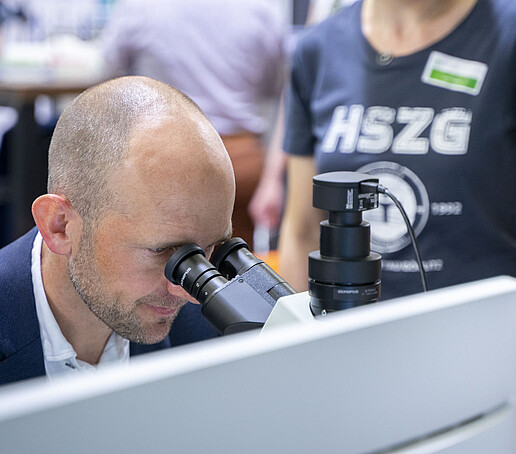 Der Landrat schaut durch ein Mikroskop.