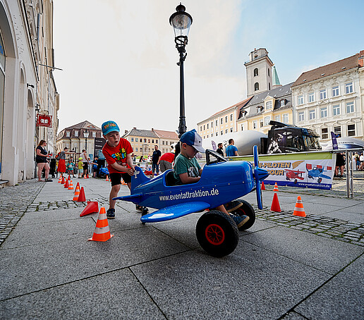 Kinder probieren ein blaues Spielzeugflugzeug aus.