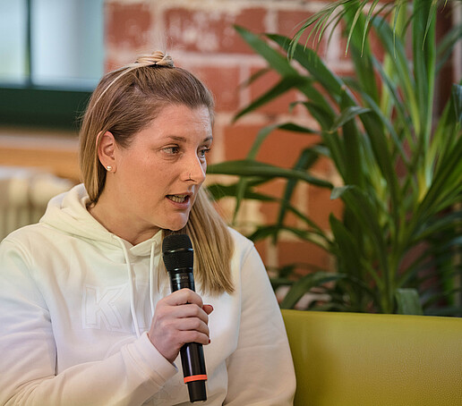 Kristin Groß mit Mikro auf dem Talk-Sofa