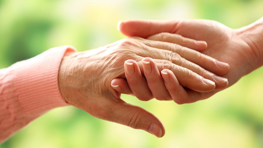 Zwei Hände, die einer alten und einer jungen Frau gehören, halten sich.