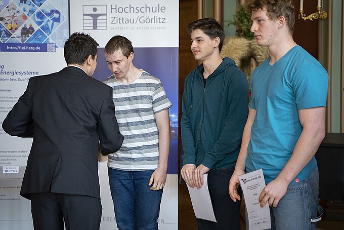 Ein Mann im Anzug überreicht Urkunden an drei junge Männer