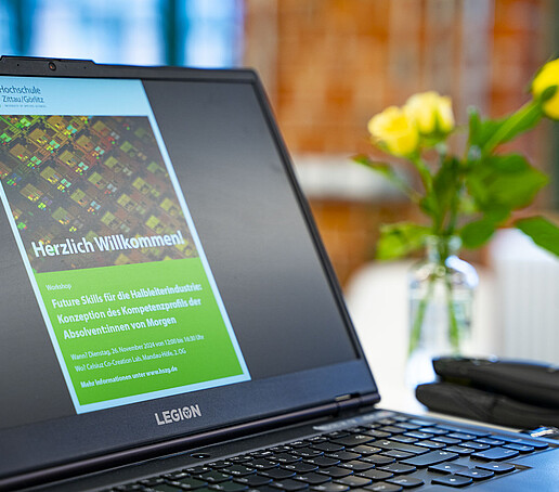 Auf einem aufgeklappten Laptop-Bildschirm ist ein Workshopflyer abgebildet.