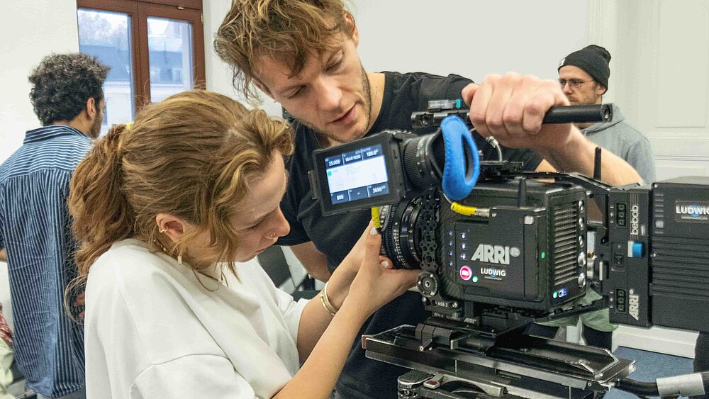 Zwei Filmstudierende probieren sich an einer Filmkamera aus.