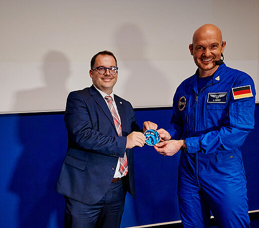 Alexander Gerst überreicht dem Rektor den Blue Dot-Missionsaufnäher im Audimax.