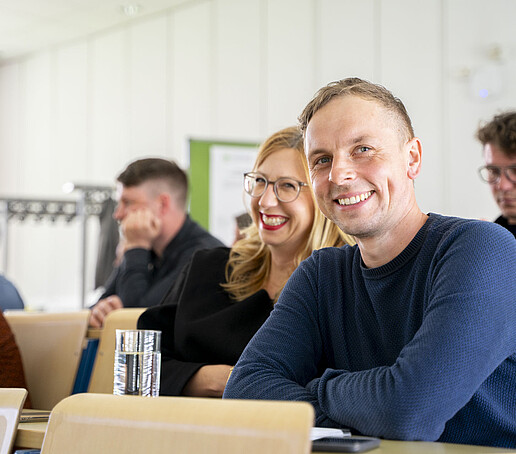 Zuhörer sitzen auf Sitzreihen im Vorlesungssaal.