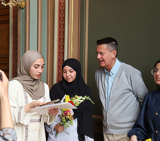 Ein Dozent unterhält sich mit einer Gruppe von Studienkollegiatinnen.