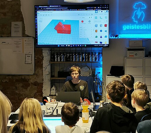 Alexander Sörgel zeigt wie die Kinder einen Einkaufswagenchip selber drucken können an einem Monitor.