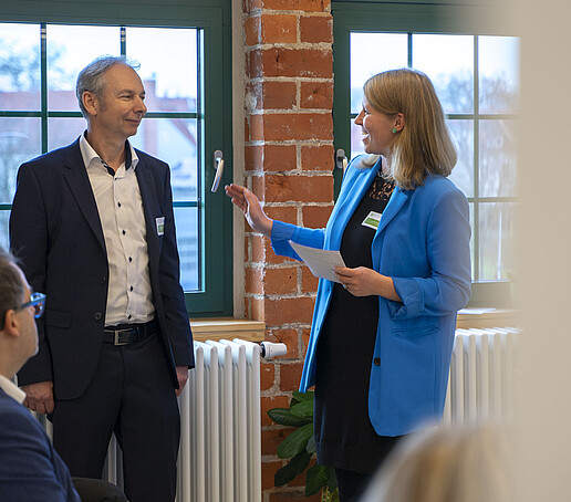 Die Moderatorin stellt einem Teilnehmenden eine Frage.