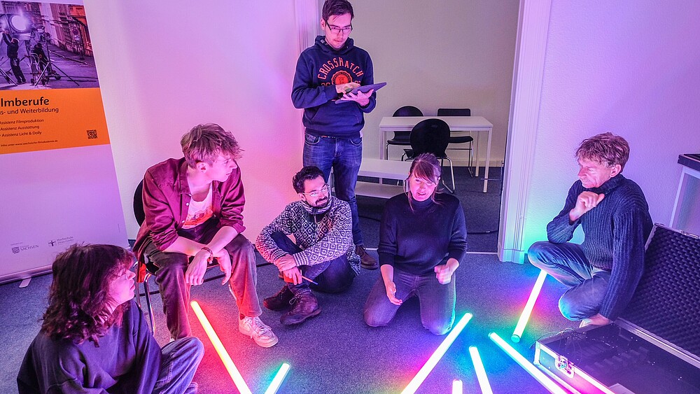Eine Gruppe Kursteilnehmende im Seminarraum mit Leuchtröhren auf dem Boden.