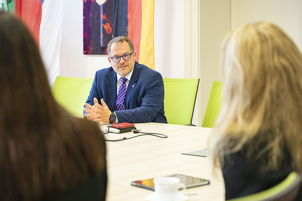 Der Rektor sitzt am Tisch im Senatssaal.