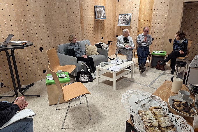 4 Personen sitzen im Raum und unterhalten sich