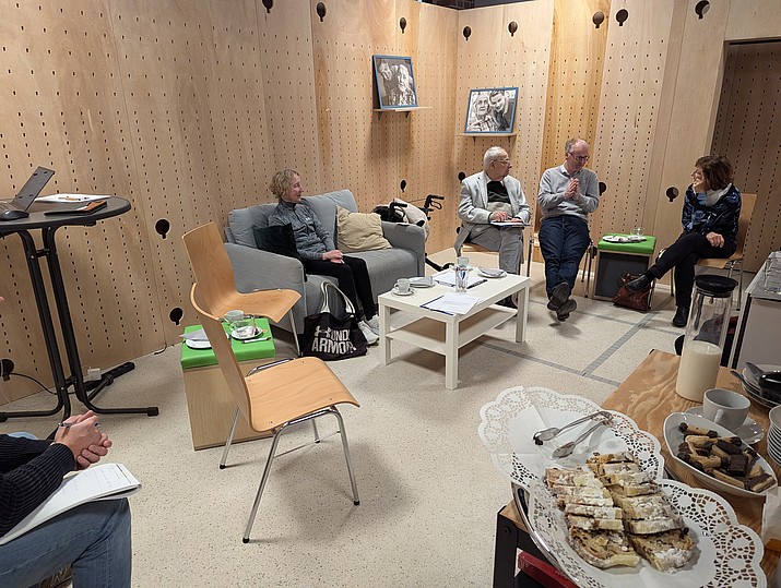 4 Personen sitzen im Raum und unterhalten sich