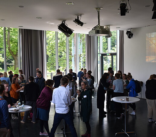 Große Grauppe an Stehtischen in der Aula