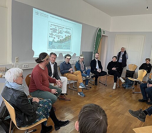 In einem Stuhlkreis sitzen Teilnehmende des Fachaustausches und diskutieren.