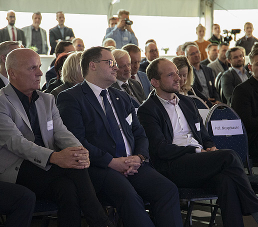 Im Publikum sitzen viele Gäste auf mehreren Sitzreihen.