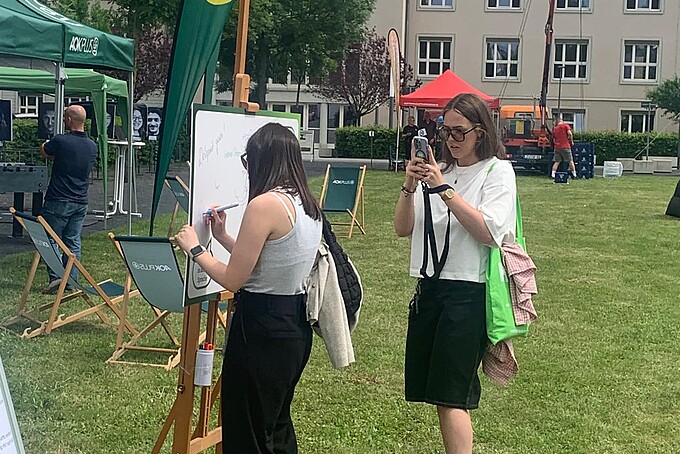 Zwei Studentinnen filmen das Festgelände mit ihren Kameras.