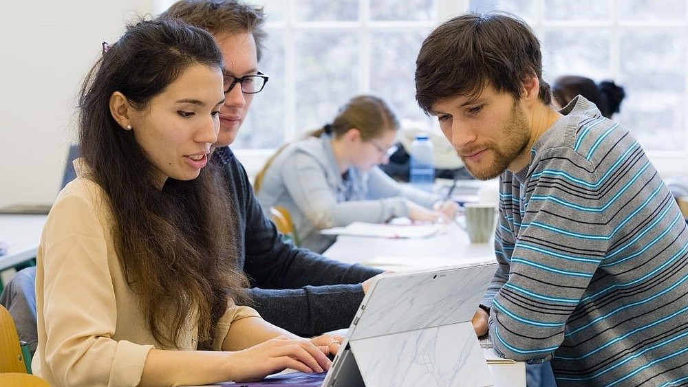 Teilnehmende am Workshop arbeiten an einem Tablet und schauen auf das Display.