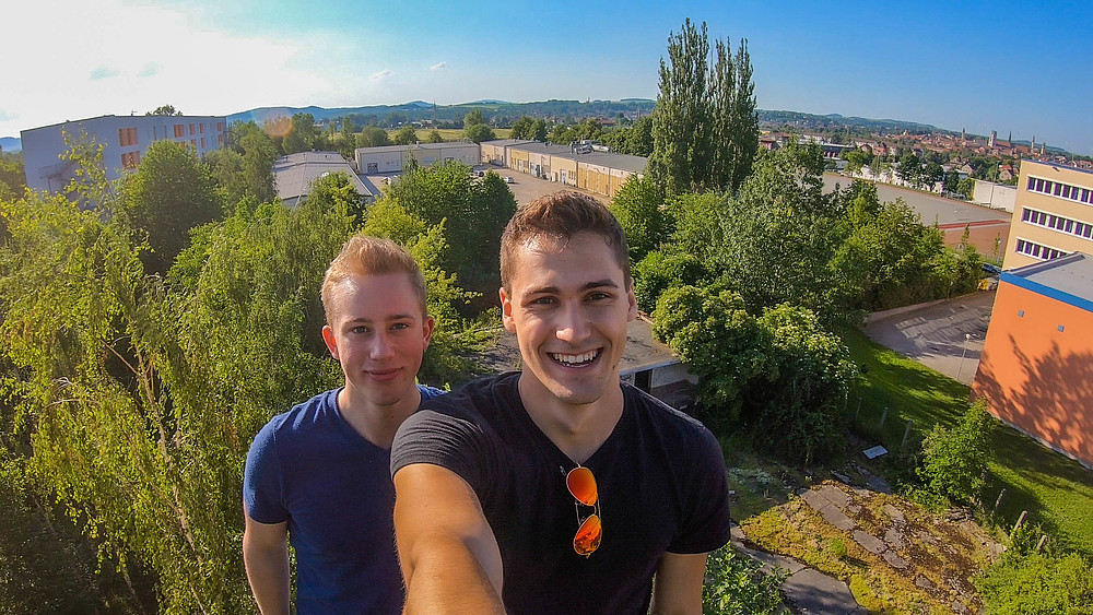 Zwei Studierende machen ein Selfie von sich über den Dächern der Hochschule.