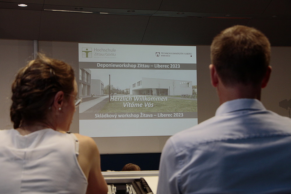 Zwei Workshopteilnehmende betrachten sich im Hörsaal die Beamerprojektion zum Kreislauf- und Deponieworkshop.