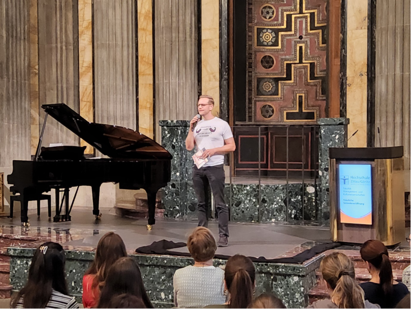 Herr Daniel Morgenroth auf der Bühne spricht zu den Studierenden