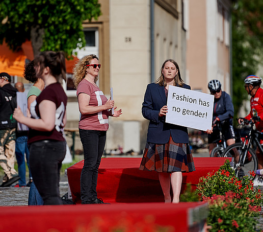 Studierende auf dem Laufsteg halten Schilder hoch.
