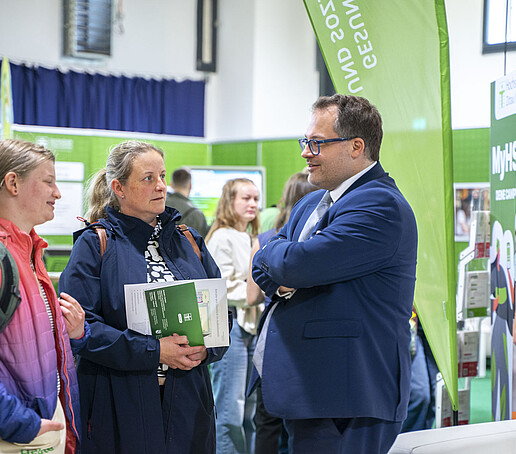 Der Rektor im Gespräch mit zwei Messebesucherinnen.