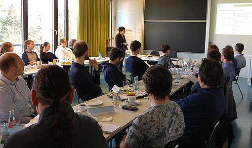 Dozentin Anke Zenker-Hoffmann hält dem Publikum im Seminarsaal einen Vortrag über die Präzisierungen der ISO 50003 zur technischen Leistungsverbesserung und deren Dokumentation. 