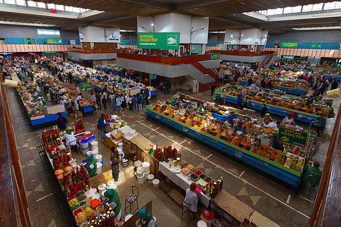 Ein Blick von oben auf eine mit Ständen gefüllte Markthalle.