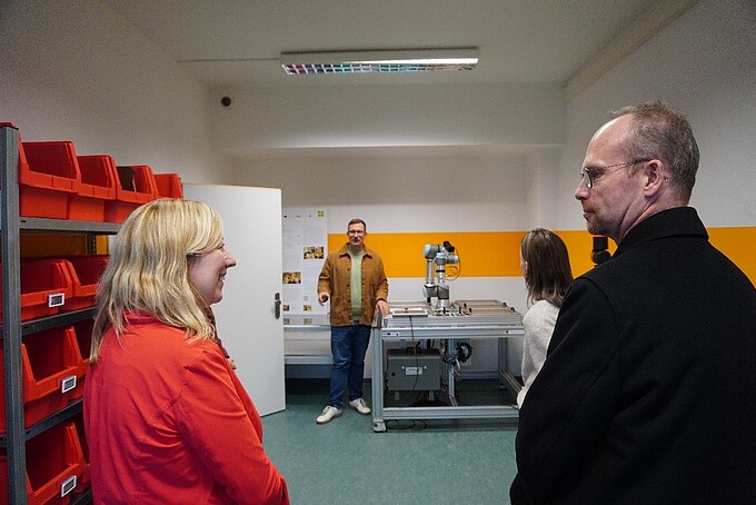 Prorektorin und Prof. Hoff schauen sich ins Gesicht, im Hintergrund steht ein SCO-TTi-Mitarbeiter neben einer Versuchsanlage.