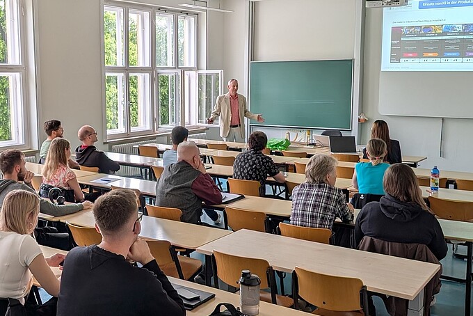 Dr. Schneider steht im Seminarraum vor den Teilnehmenden und referiert über den Einsatz von KI in der Produktion.