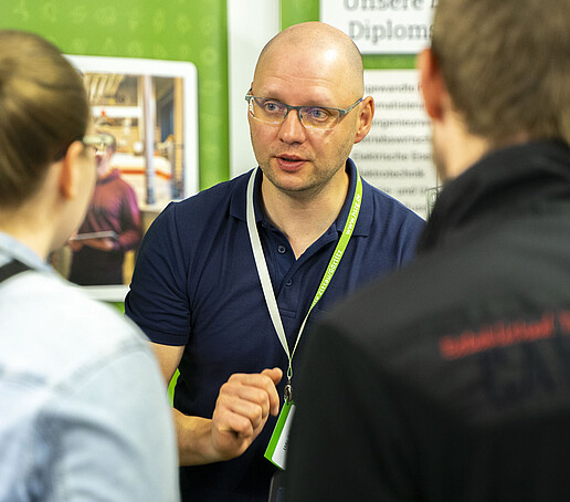 HSZG-Mitarbeiter im Gespräch mit Studieninteressierten am KIA-Stand.