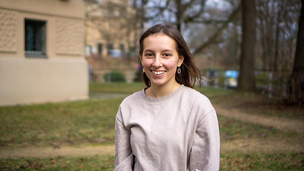 Luisa Walter sitzt im Park und lächelt in die Kamera.