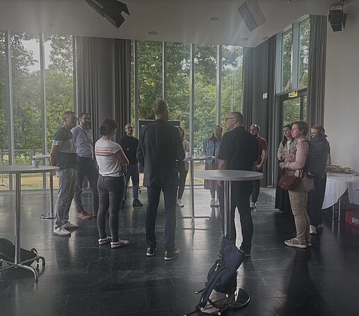 Tagungsteilnehmer stehen in der Pause um Stehtische