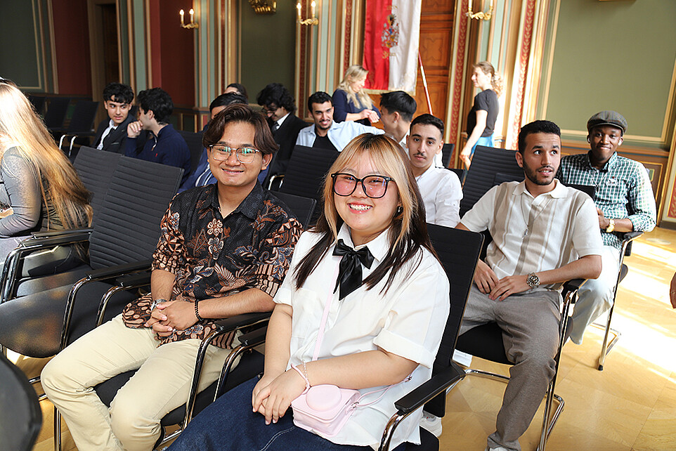 Zwei frischgebackene Absolventinnen genießen gemeinsam mit ihren Kommilitoninnen den besonderen Moment im festlich geschmückten Saal.