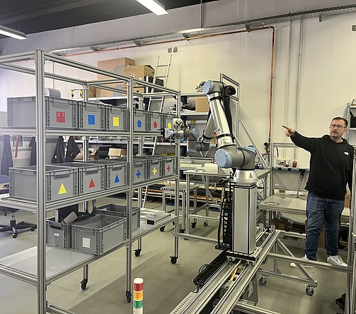 Mitarbeiter zeigt auf verschiedene Recyclingboxen