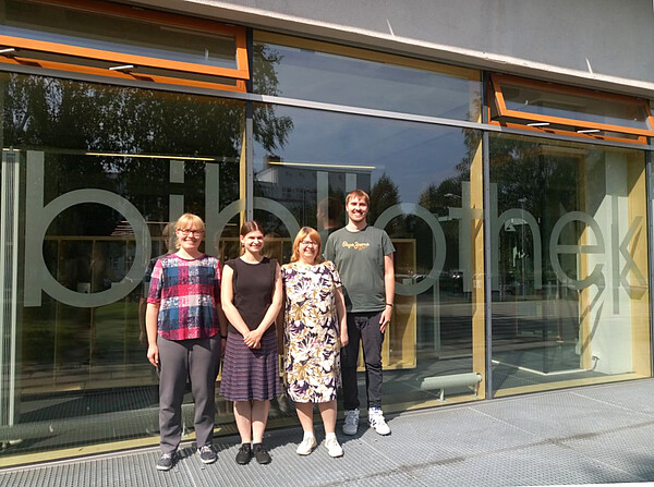 Vier Personen vor Bibliotheksgebäude