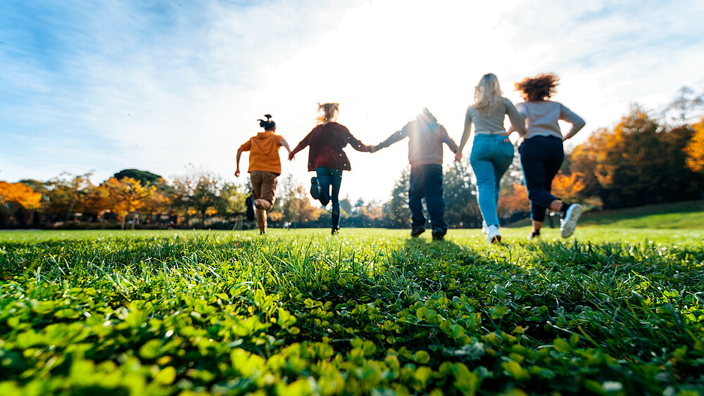 Junge Leute rennen über eine Wiese.